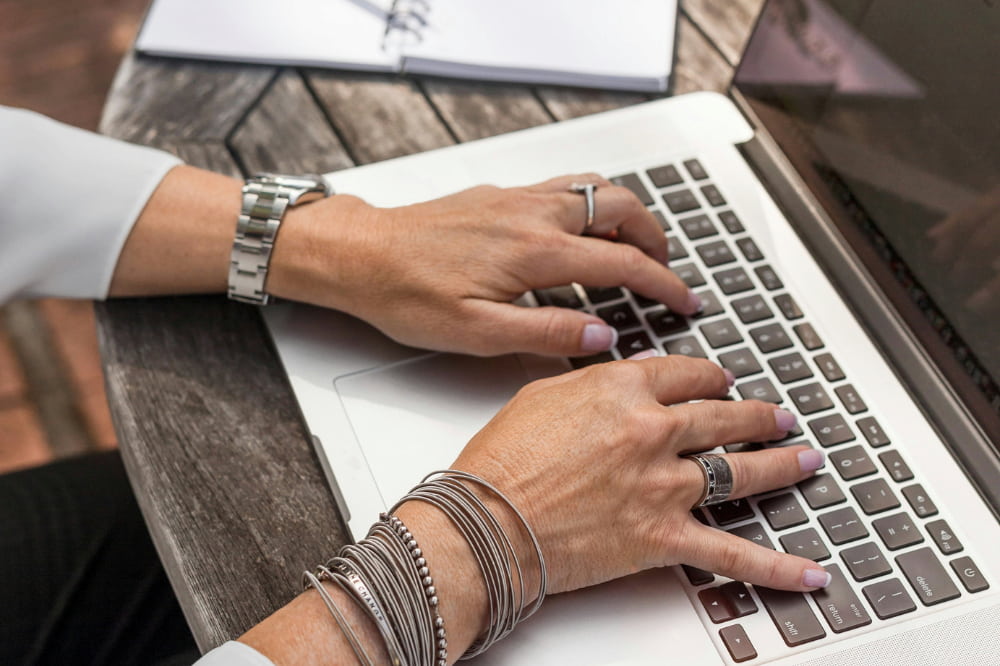 A woman's hands typing on a laptop.